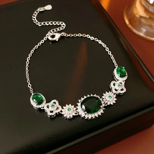 Macro detail of silver flower bracelet with green oval gemstone and white zircon