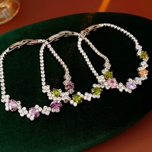 Close-up of geometric bracelets with colorful zircon stones on green velvet display