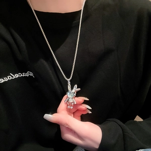 Silver rabbit astronaut necklace with blue cat-eye stone worn on a black sweater
