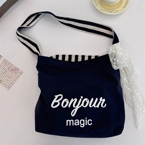 Detail of navy canvas tote with Bonjour magic print and striped handles in French style