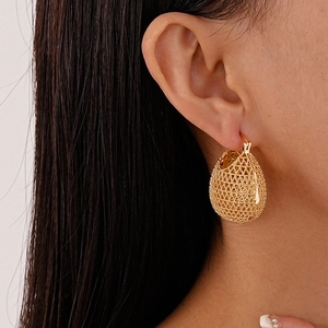 Macro shot of French vintage gold teardrop earrings with intricate woven mesh metal texture