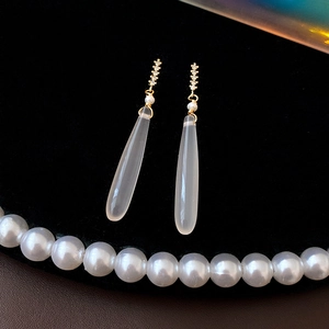 Detail of drop earrings with pear-shaped resin pendant, small pearls and sparkling rhinestones