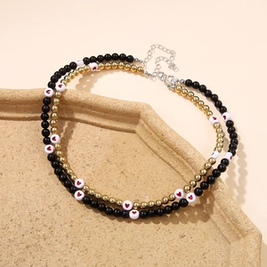 Detail of layered Christmas necklace with black beads and red heart pendant on tray