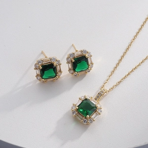 Detail of gold jewelry set with emerald green gemstone and cubic zirconia accents