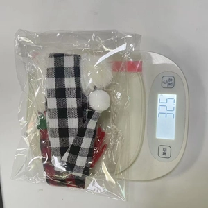 Detailed view of small plush Christmas ornament with plaid scarf on a digital scale