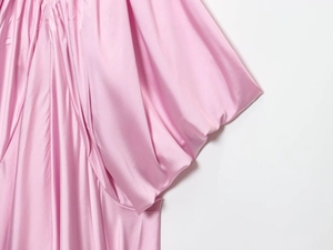 Detail shot of light pink satin fabric showing soft drape and glossy silk-like texture