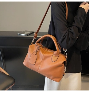 Detail of classic brown lychee texture leather tote bag with metal buckles and handle