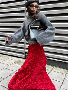 Detail of red textured long skirt with petal-like material and grey knit sweater outfit