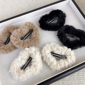 Detail of plush heart-shaped hair clips in beige, khaki and black on a display tray