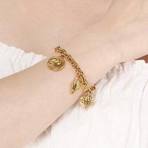 Golden stainless steel bracelet with shell, wave disk and textured heart pendants on wrist
