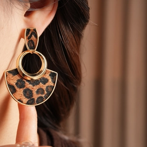Close-up of stylish leopard print fan-shaped earrings with gold metal rings on model