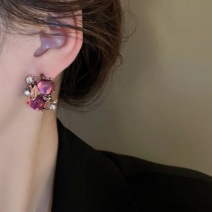 Detail of vintage flower earrings with pink gems and gold finish on female model
