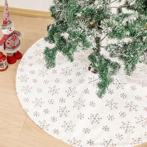 Plush white Christmas tree skirt with colorful sequin snowflake embroidery on wood floor