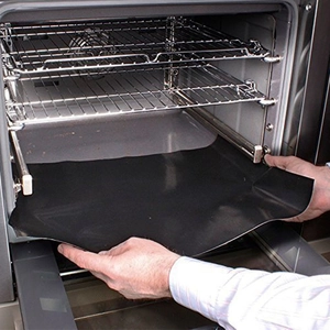 Black non-stick fiberglass BBQ oven mat 40x50cm being placed inside a clean modern oven
