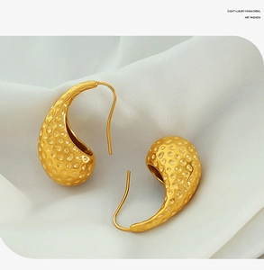 Close-up of vintage waterdrop earrings with hammered gold texture on silk
