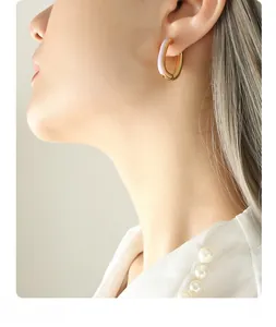 Close-up of elegant U-shaped gold hoop earring with light purple enamel on model