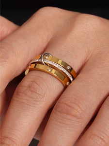 Close-up of stacked stainless steel rings featuring gold bands and crystal pavé detailing