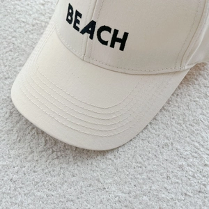 Close-up of black BEACH embroidery on cream beige cotton canvas baseball cap