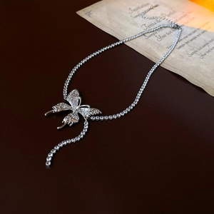 Close-up of silver butterfly tassel necklace with sparkling rhinestones on leather background