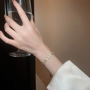Détail d'un bracelet doré avec des maillons en forme de H et des cristaux scintillants