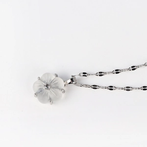 Macro detail of silver necklace featuring a translucent white shell flower pendant