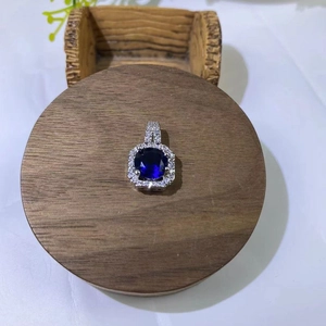 Close-up of a silver pendant necklace with a blue gemstone surrounded by pavé zircons