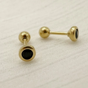 Macro shot of gold-tone titanium steel dumbbell stud with black cubic zirconia stone