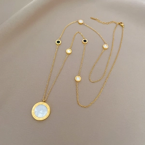Macro view of gold titanium steel necklace with white shell pendant and Roman numerals