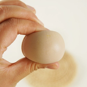 Squishy realistic egg toy made of soft PU material being squeezed for stress relief