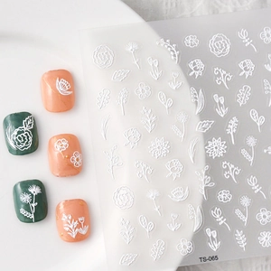Macro detail of white 5D embossed nail stickers with intricate floral and leaf designs