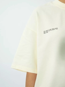 Λεπτομέρεια από οργανικό βαμβακερό t-shirt σε σπασμένο λευκό με χαμηλωμένους ώμους