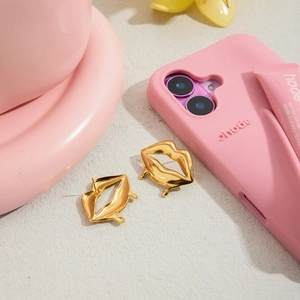 Détail de boucles d'oreilles lèvres dorées avec effet gouttes sur fond texturé
