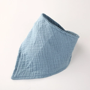 Détail d'un bavoir en mousseline de coton bleu clair montrant la texture douce du tissu