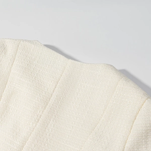 Dettaglio della trama in tessuto tweed crema elegante e del motivo a maglia sul completo