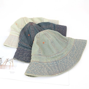 Three vintage denim bucket hats in navy, teal, and beige with contrast orange stitching