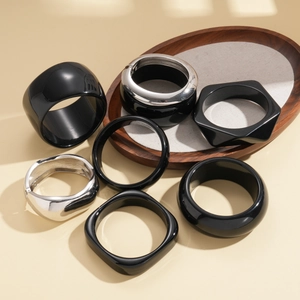 Modern resin and silver geometric bangles in black and metallic finishes set on wood