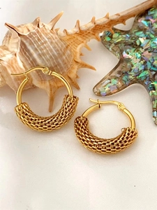 Detail of gold hoop earrings with woven chain texture on white background with shells
