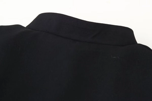 Detail shot of black high-collar jacket fabric showing premium twill texture and stitching