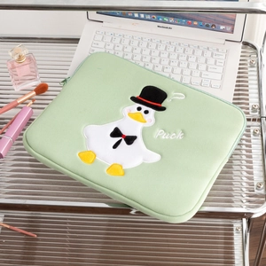 Detail of light green iPad sleeve with cute embroidered duck and zip closure on the table