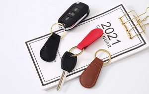 Close-up of PU leather teardrop keychains in black, red, and brown with gold rings