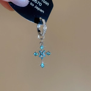 Macro shot of silver cross earring with blue gemstones and fine diamond micro-paving