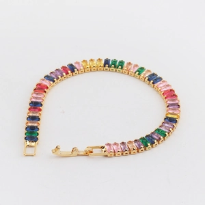Close-up of rainbow tennis bracelet with multi-color emerald-cut stones and gold plating