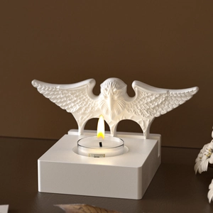 Détail d'un bougeoir aigle en résine blanche avec une bougie chauffe-plat allumée
