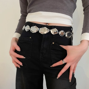 Gros plan d'une ceinture chaîne en métal argenté facetté sur un mannequin stylé