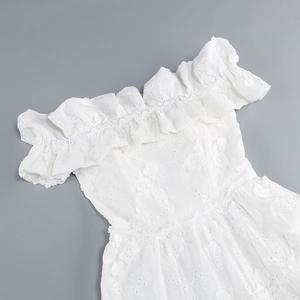 Macro shot of white off-shoulder lace dress with intricate floral eyelet embroidery details
