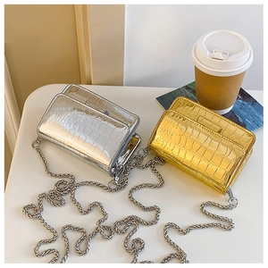 Close-up of mini croc-effect patent leather chain bags in glossy silver and gold finishes