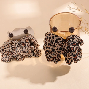 Leopard print petal tassel earrings hanging on a glass for an autumn aesthetic look