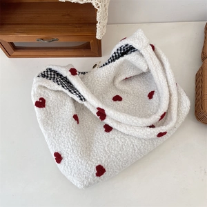 Close-up of white plush tote bag with red heart embroidery and plaid fabric lining