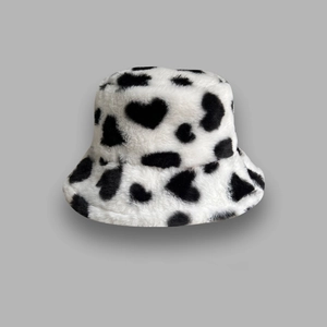 Detail of white faux fur bucket hat with black heart cow print patterns