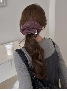 Deep burgundy striped fabric scrunchie worn by model in a cozy indoor setting